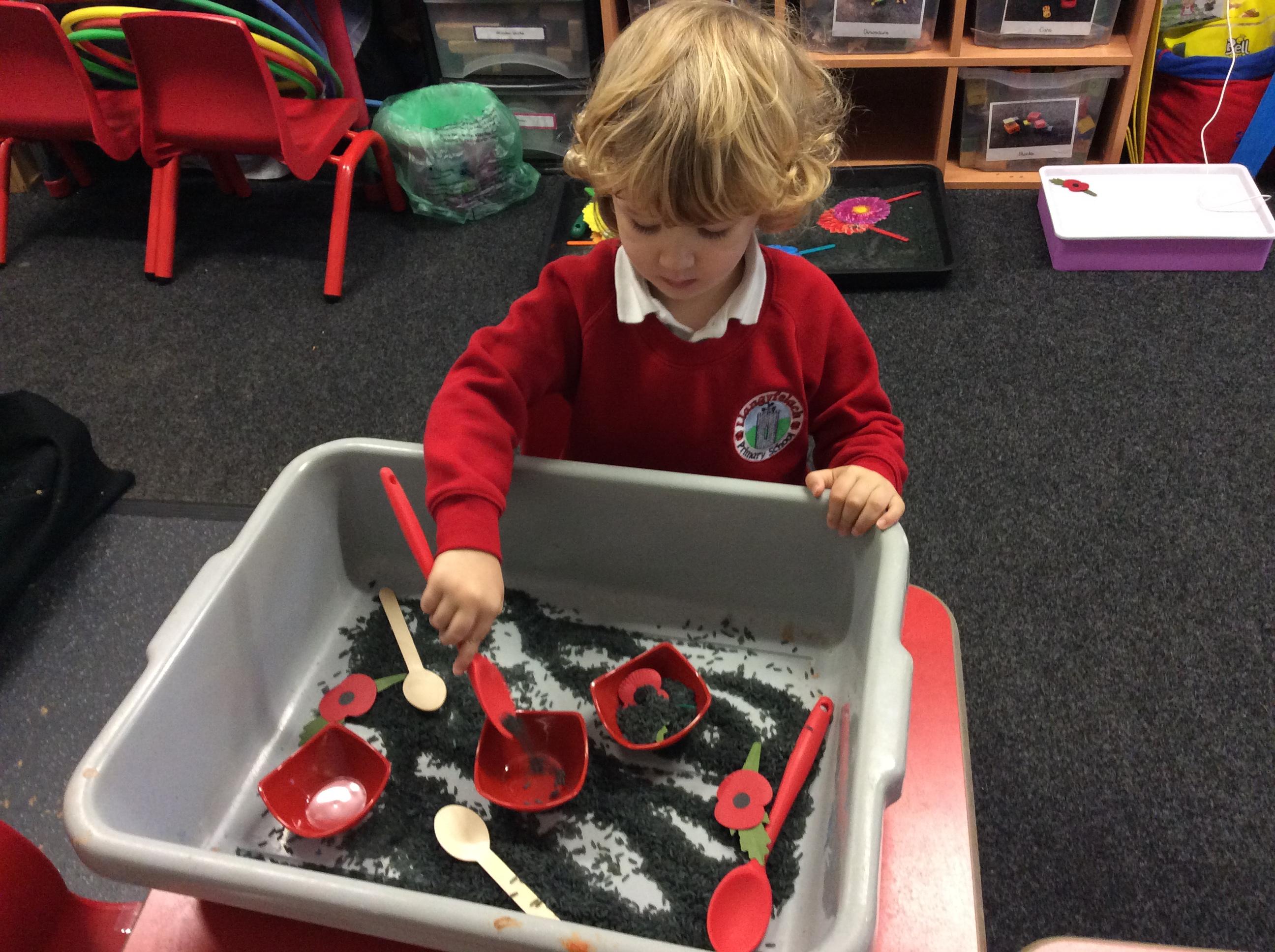 Making a poppy in the coloured rice. 